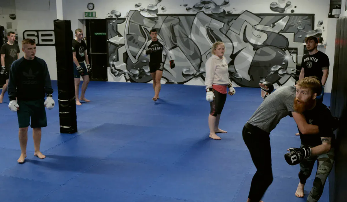 An MMA class working in the clinch on the blue mats